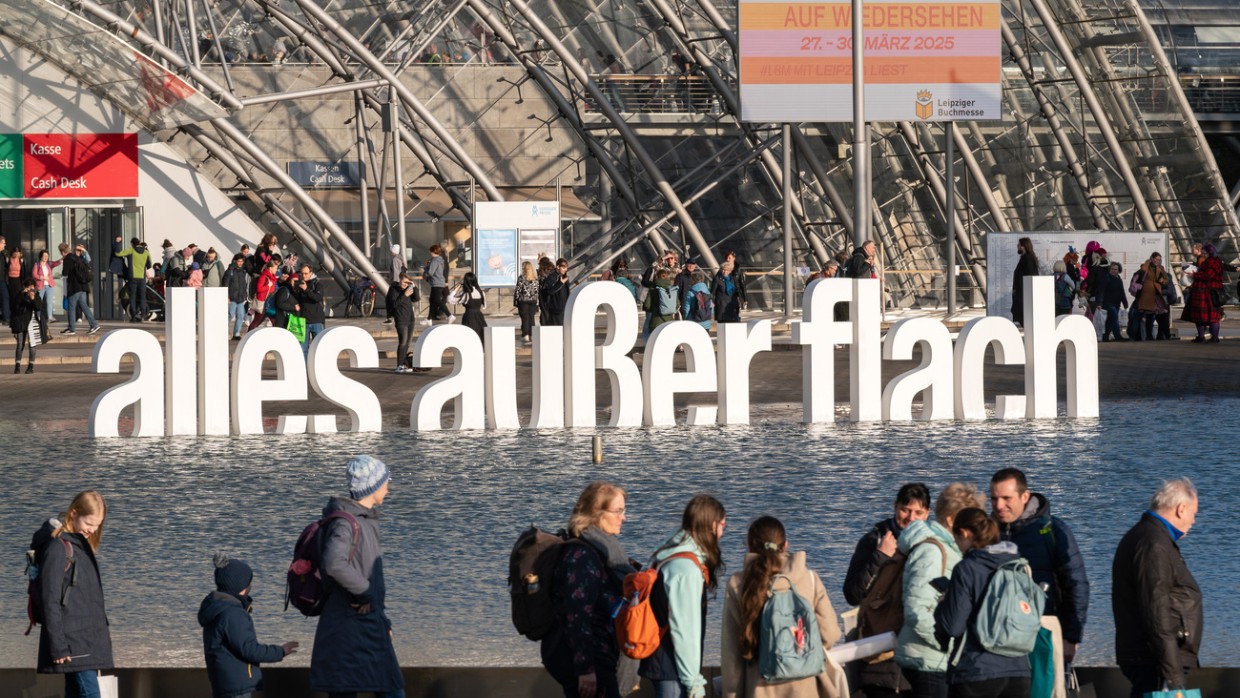 Außenansicht von Glashalle und Messesee mit Fokus auf den Slogan "alles außer flach" während der Leipziger Buchmesse 2024