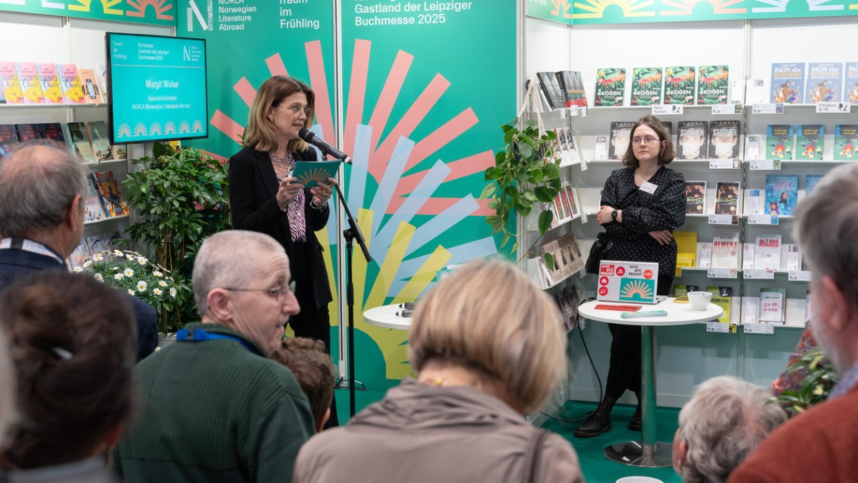 Margit Waslo spricht am Mikrofon bei der Eröffnung des Messestandes des Gastlandes 2025 Norwegen mit vielen Zuhörer:innen auf der Leipziger Buchmesse 2024