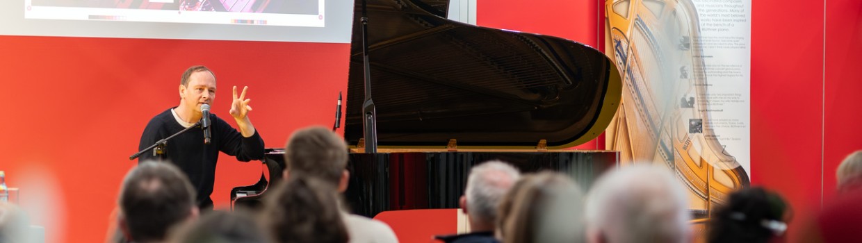 Pianist am Flügel auf einer Forumsbühne vor vollbesetztem Publikum während der Leipziger Buchmesse 2024