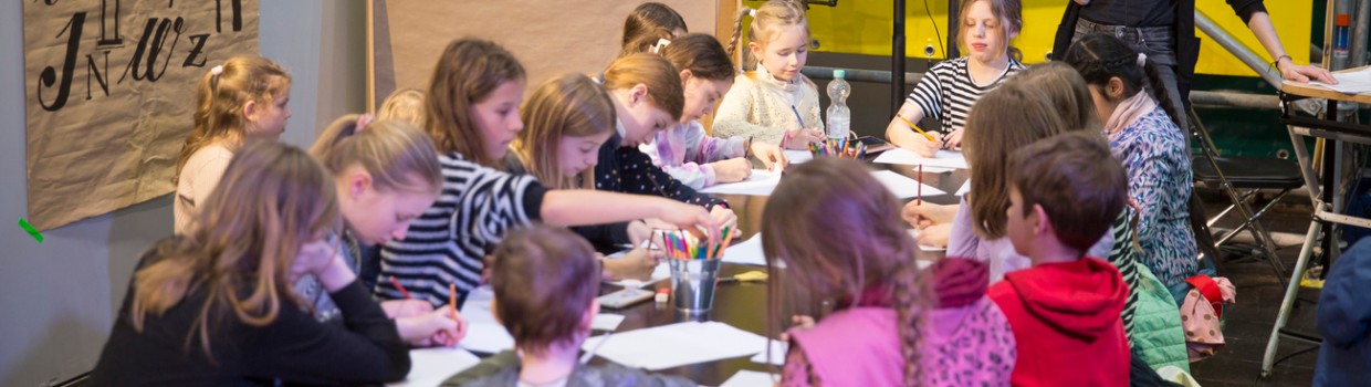 Kinder malen an einem großen Tisch im UVERSE auf der Leipziger Buchmesse 2024
