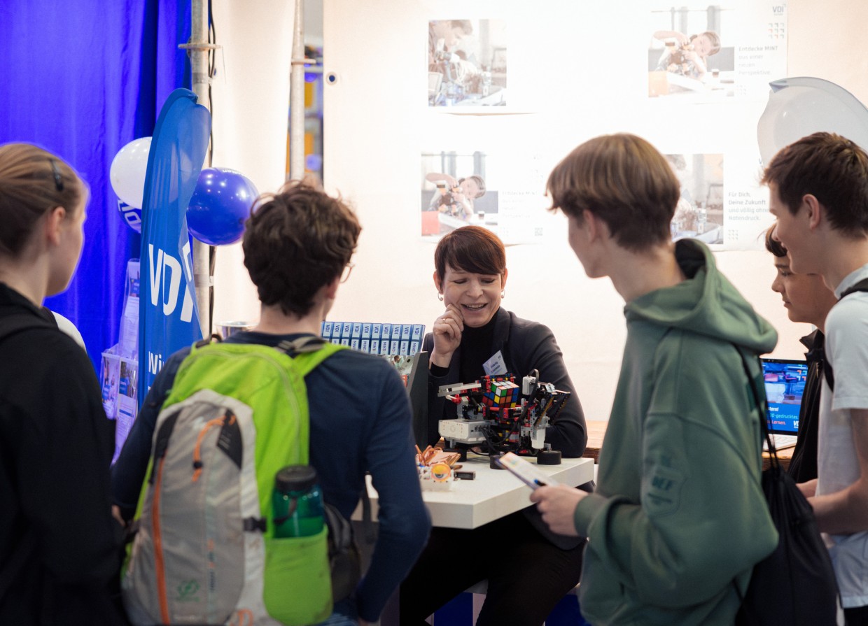 VDI Messestand mit Ausstellerin und mehreren jungen Besucher:innen auf der Leipziger Buchmesse 2025 VDI Messestand mit Ausstellerin und mehreren jungen Besucher:innen auf der Leipziger Buchmesse 2025